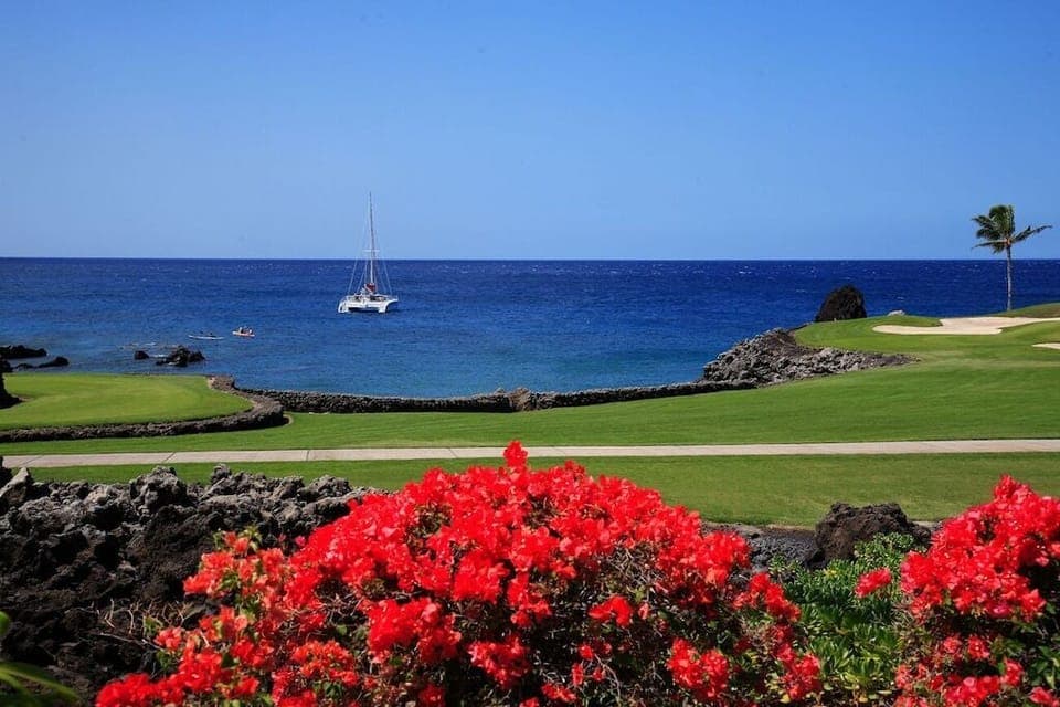 Tee off in paradise where manicured greens meet lava rock cliffs and sailboats drift in the blue horizon.