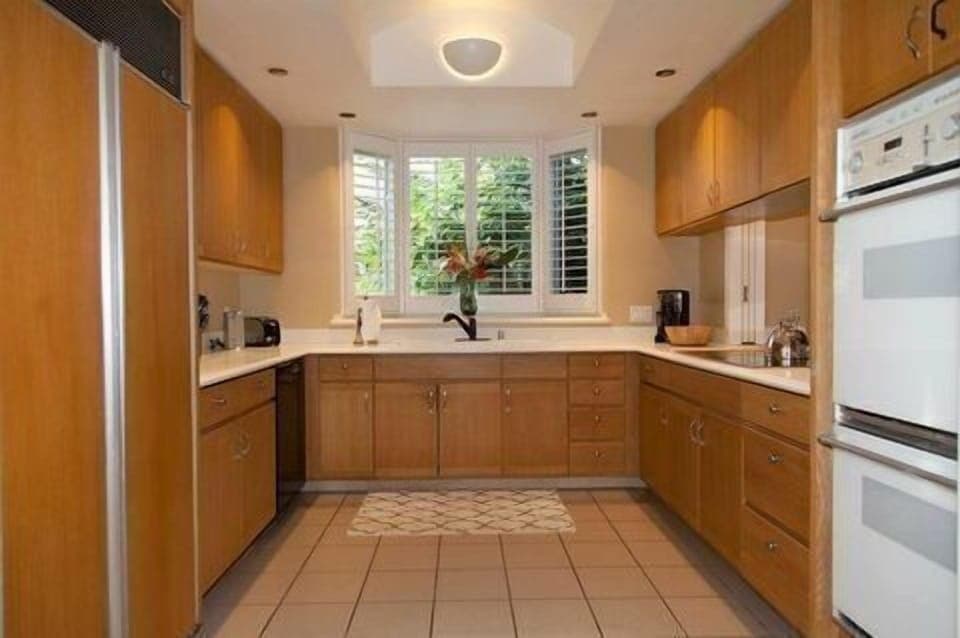 Cook up paradise in this spacious, sunlit kitchen framed by garden views and warm wood finishes.