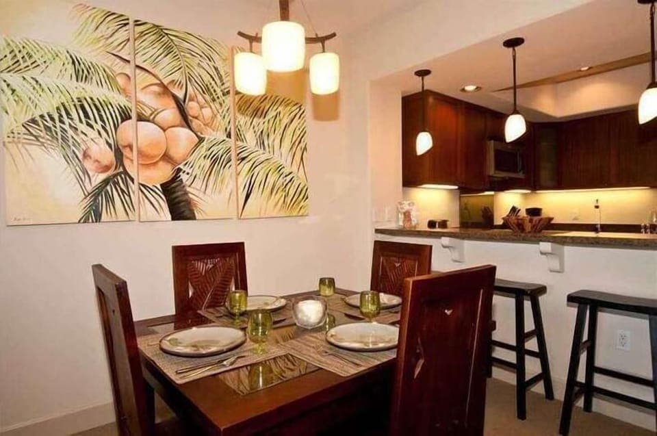Gather for meals under warm pendant lights and palm inspired art, with bar seating at the kitchen.

