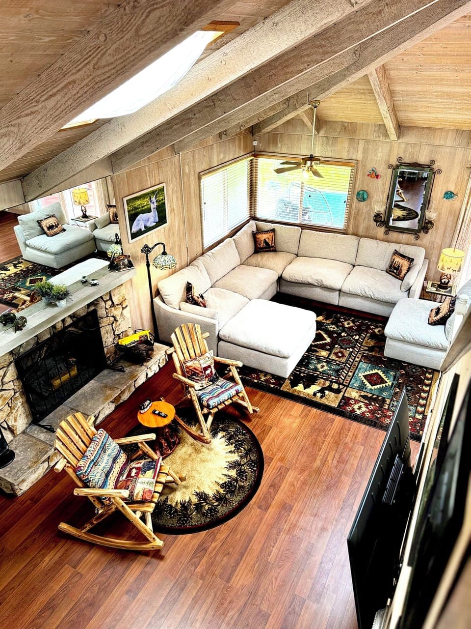 Warm cabin living room with fireplace, skylights, and cozy rustic seating.