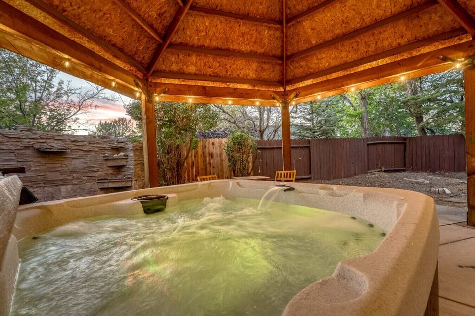 Unwind under the twinkle lights in your own backyard haven—complete with a soothing hot tub and peaceful garden vibes.