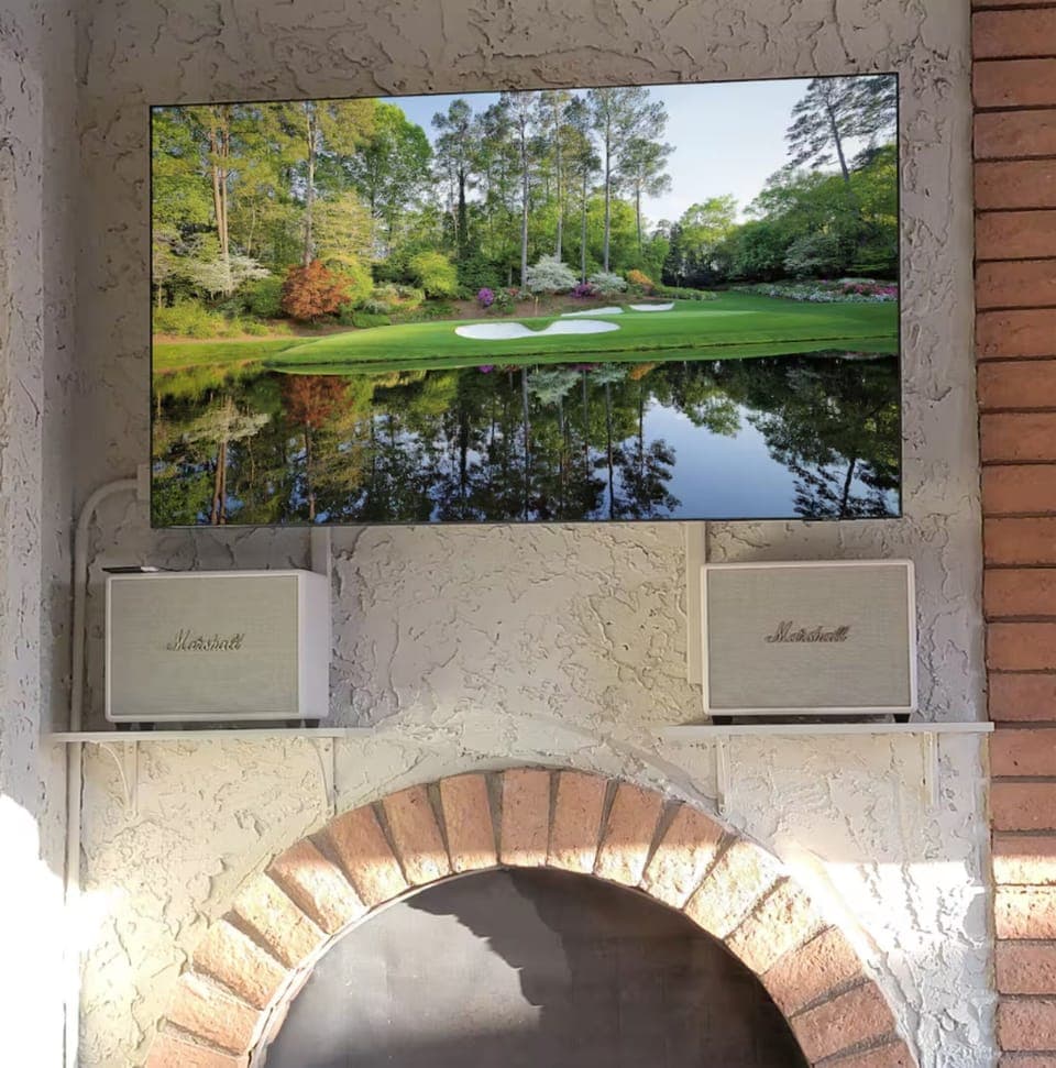 The central interior courtyard doubles as an indoor-outdoor home theater, featuring an 80-inch Samsung Smart TV paired with top-of-the-line cream-colored Marshall Woburn tower speakers in coupled left-right stereo mode, delivering immersive  sound.