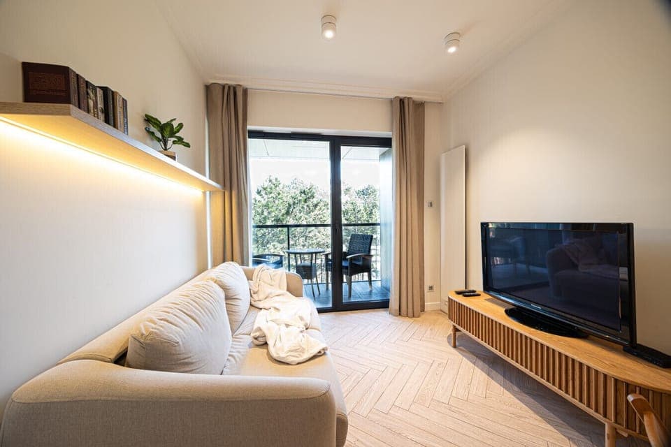 Cozy living room with terrace access – unwind with forest views and a glimpse of the sea.