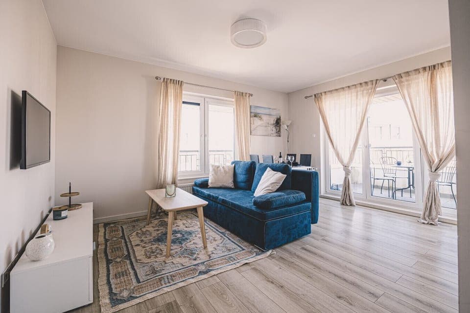 Spacious living room with a comfortable sofa bed and large TV – the perfect family retreat after a day on the beach in Ustronie Morskie.