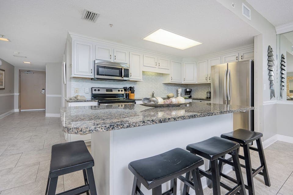 Gather around the sleek granite island with bar stools for casual meals or drinks in this inviting kitchen space