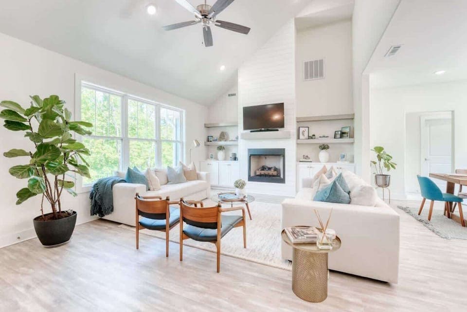Step into serene comfort with this light-filled living space featuring vaulted ceilings, a cozy fireplace, and stylish decor. 
