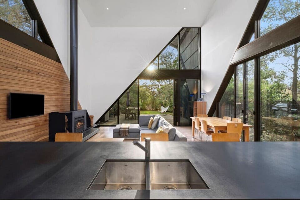 Expansive glass walls frame the open-plan living and kitchen space, filled with natural light and warmth.