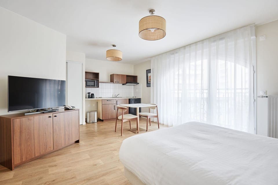 Bright studio with a cozy double bed and flat-screen TV—perfect for couples or solo travelers seeking Parisian comfort.