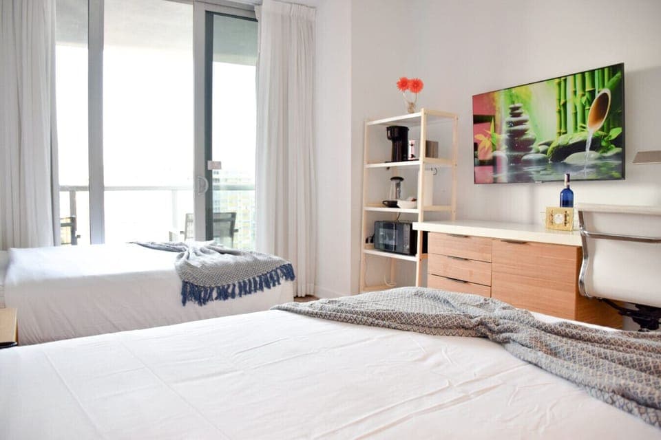 Spacious bedroom with balcony access and Smart TV.
