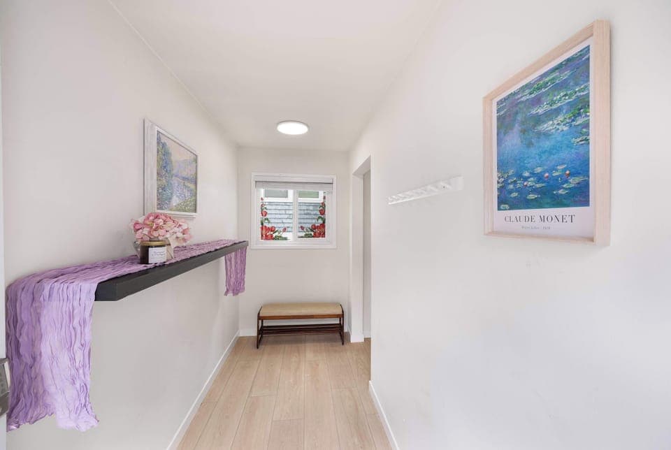 Simple designed hallway lined with few paintings，and windows framed with flower stickers.