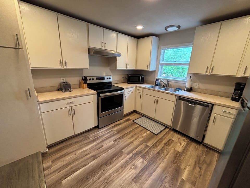 Cozy kitchen with stove, dishwasher, microwave, and drip coffee maker.