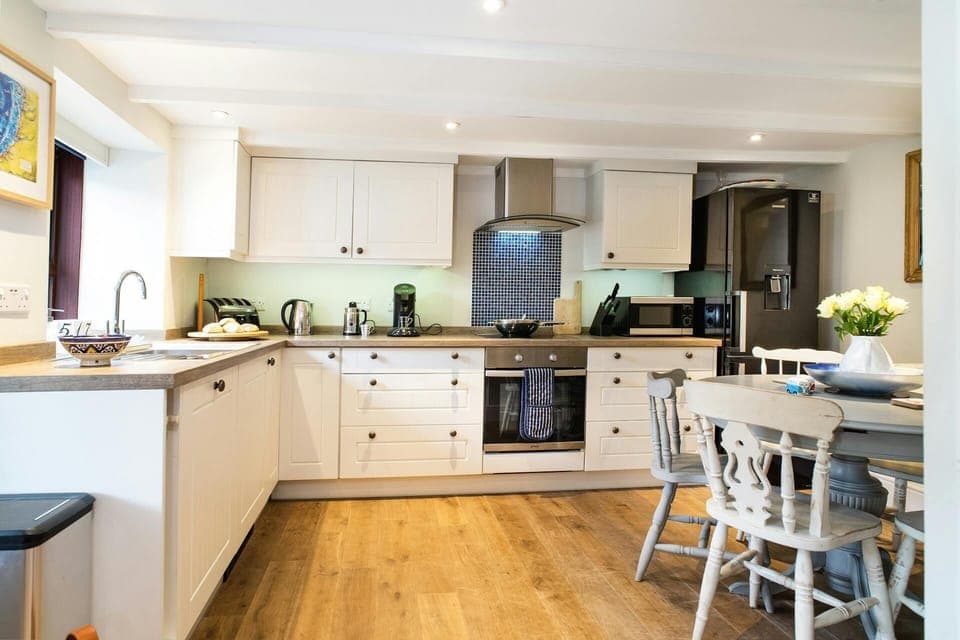 Kitchen and dining area with table and chairs, cooker, sink, fridge