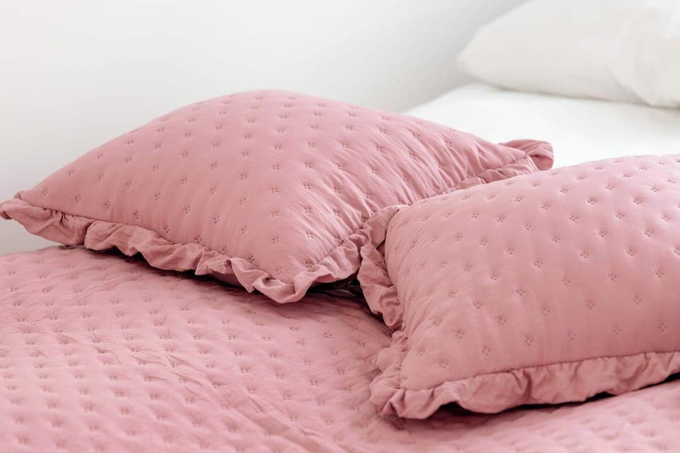 A close-up of pink pillows on a white bed, offering a soft and cozy look.