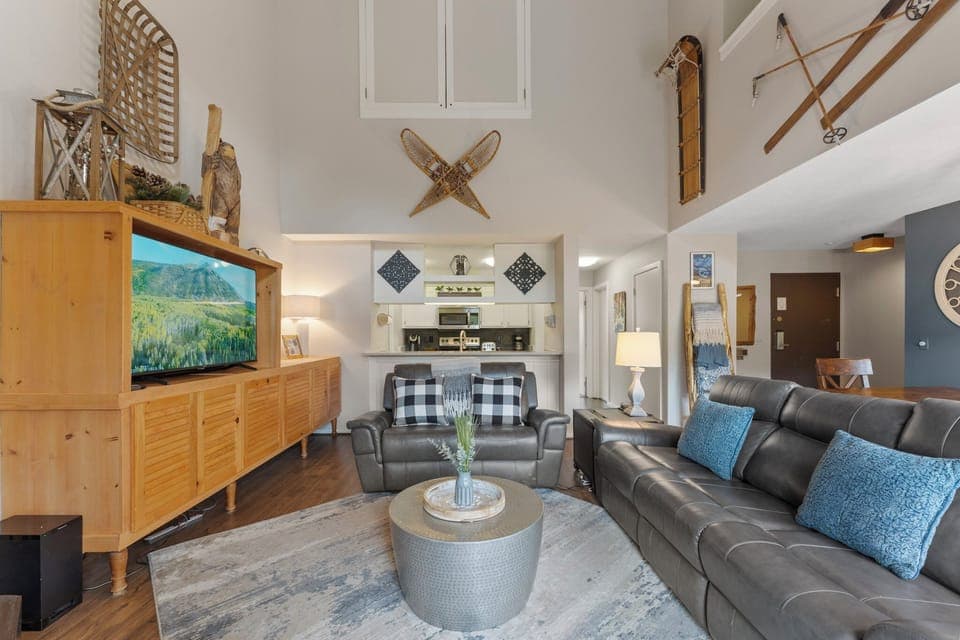 The living room features a wood burning fireplace, large smartTV, ample seating, and access to the private balcony.