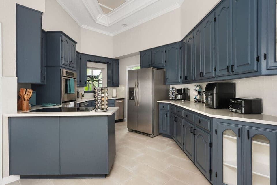 Spacious gourmet kitchen with stainless steel appliances, ample counter space, and modern navy cabinetry—perfect for home-cooked meals or entertaining in style