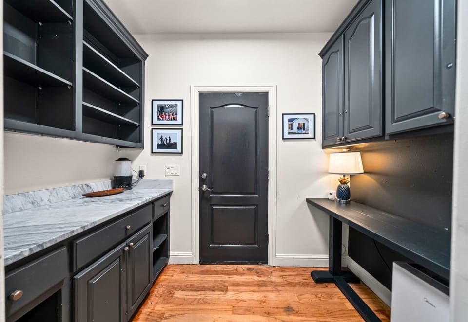 Tucked-away office and prep area with ample cabinetry, a marble worktop, and dark tones that create the perfect blend of utility and design.