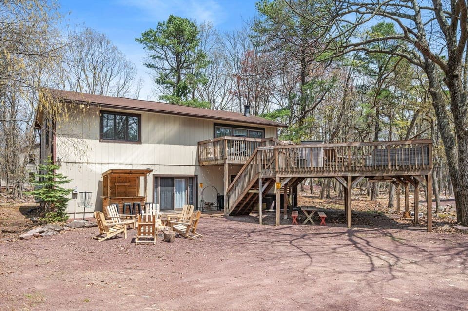 Gather around the fire pit and unwind beneath the trees in this wooded backyard retreat