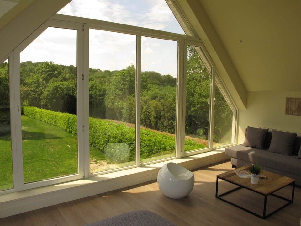 Fenêtre panoramique avec vue sur les bois et l'Abbaye du Mont des Cats. Des stores sont présents pour l'occultation si nécessaire.
