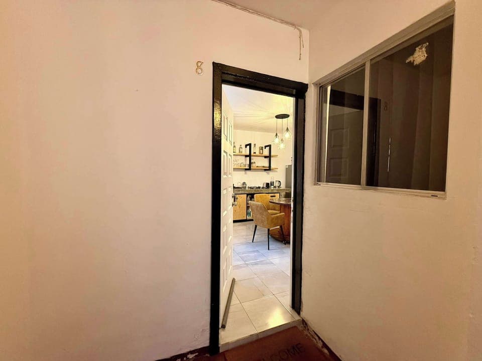 Entrada del departamento (con vista a sala de estar; mesa con 4 sillas, escritorio individual con silla, lámpara de lectura)