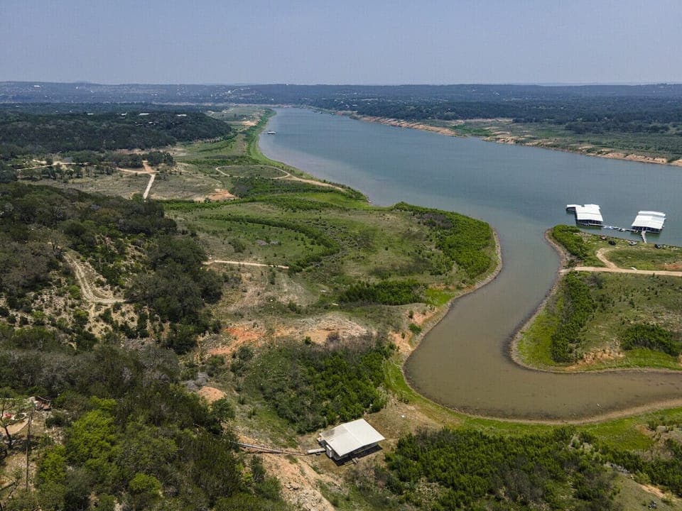 You’ll spot the firepit in the corner—perfect for evenings under the stars! The dock is currently resting on dry land due to lower water levels, but guests can still easily access the water for swimming and lakeside fun.