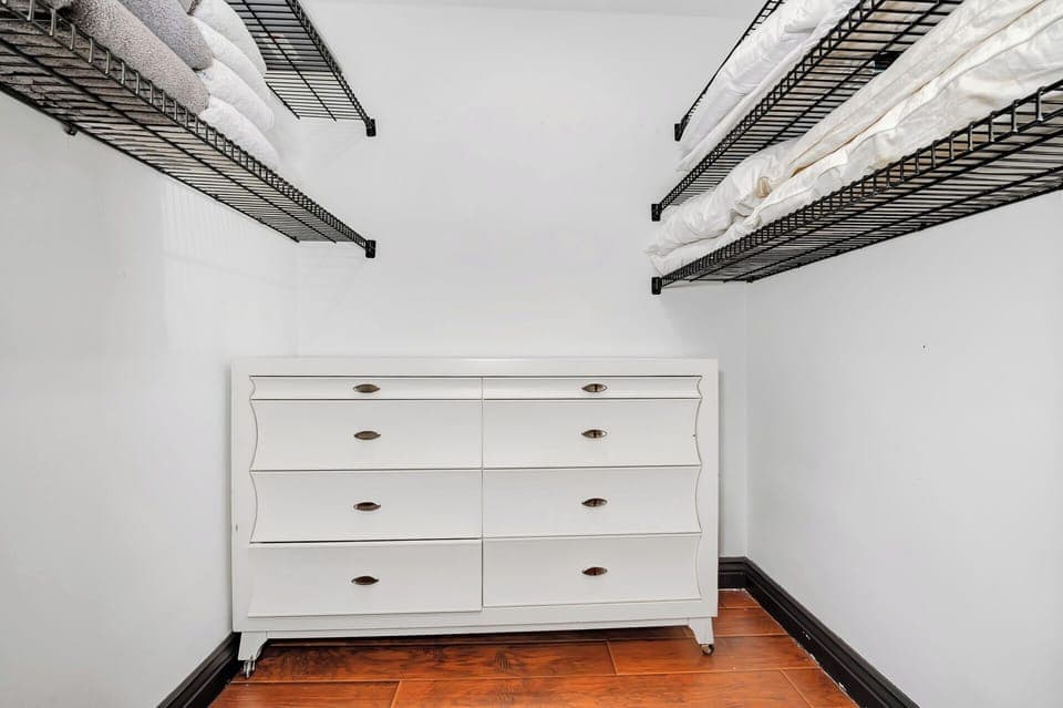 Walk-in closet with dresser and open shelving for extra storage.
