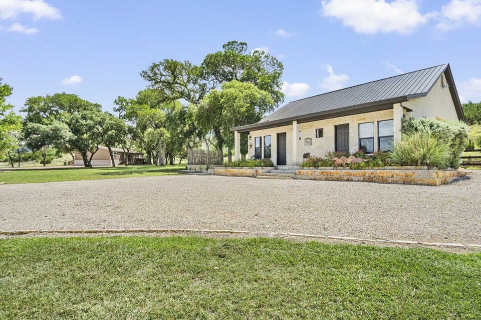 Discover your serene retreat! This charming vacation rental boasts a spacious gravel driveway, surrounded by lush greenery and mature trees, offering a peaceful escape with ample space