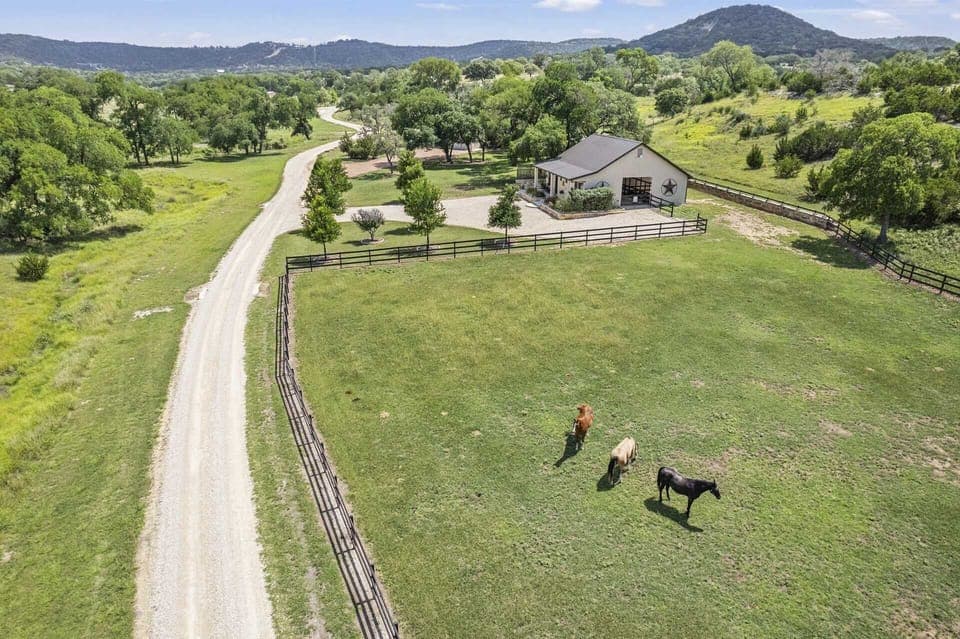 Escape to this serene countryside retreat, offering expansive green pastures where horses graze peacefully, a long private driveway, and stunning views of rolling hills and lush trees