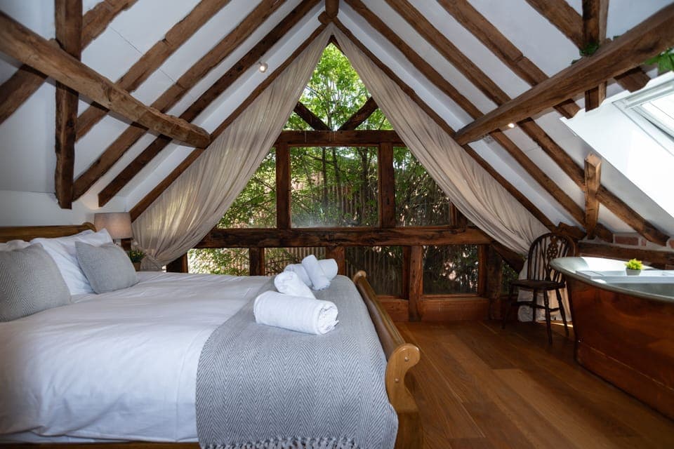 Master bedroom with luxurious treehouse vibes, large windows and a stunning copper bath — perfect for private, romantic escapes