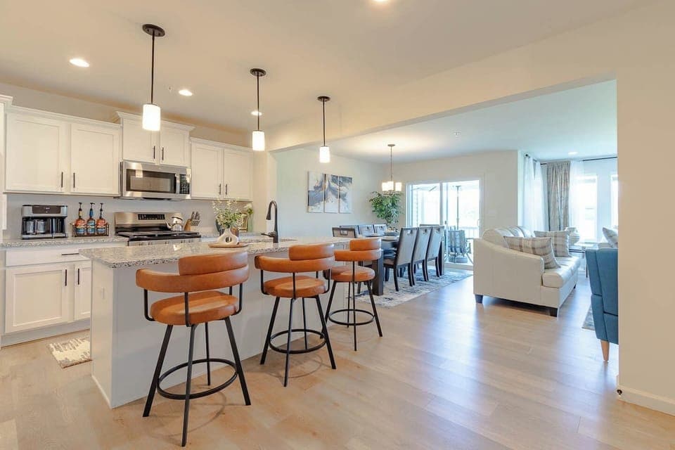 Step into an open-concept space where a sleek kitchen flows seamlessly into the dining and living areas, perfect for gathering, entertaining, or relaxing with the whole group.