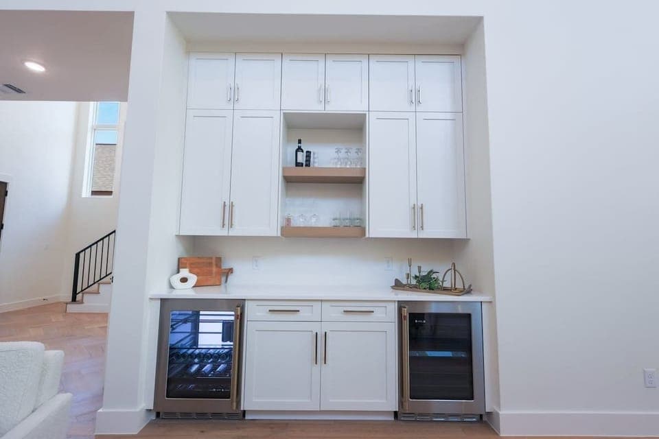Cheers to convenience!  This built-in dry bar features dual wine fridges, open shelving for glassware, and plenty of storage—perfect for entertaining or winding down in style.
