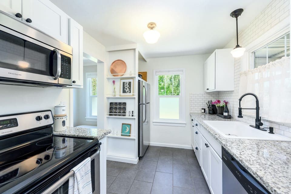 Fully equipped kitchen with stainless steel appliances and farmhouse sink basin.