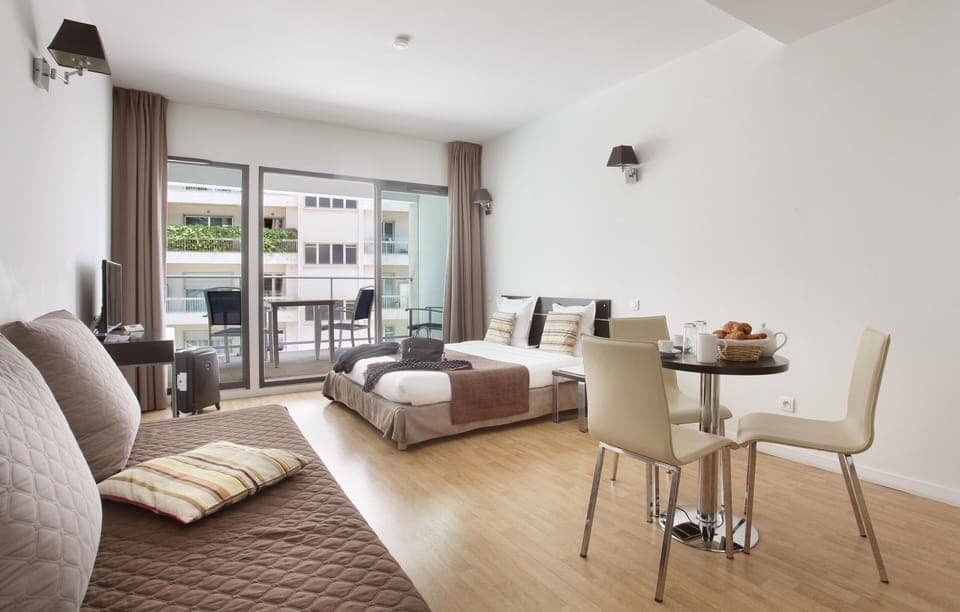 Step into a sunny studio with seating and dining space, opening onto a private balcony for fresh-air moments.