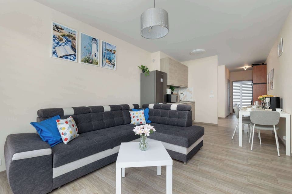 A living room with a dark gray sectional sofa, a small white coffee table, and decorative wall art above the couch.
