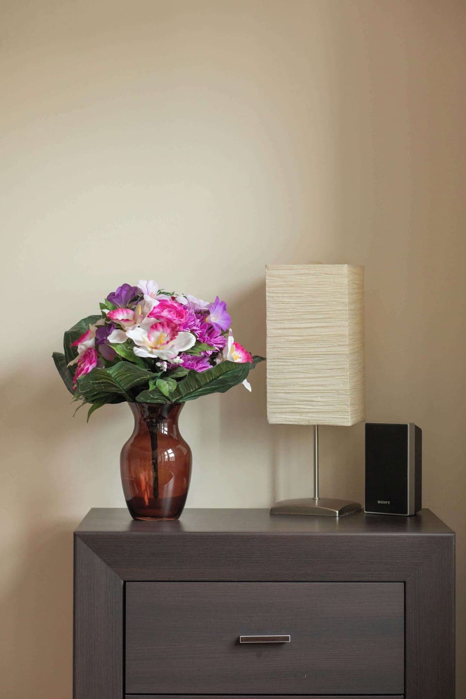 A close-up of a bedside table with a vase of fresh flowers, adding a touch of elegance. The soft lighting creates a cozy and intimate atmosphere.
