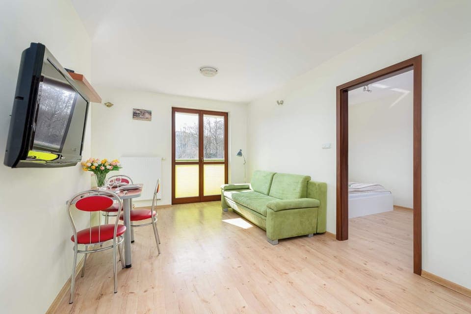 Spacious living room with a sofa bed, TV, dining area and exit to balcony.