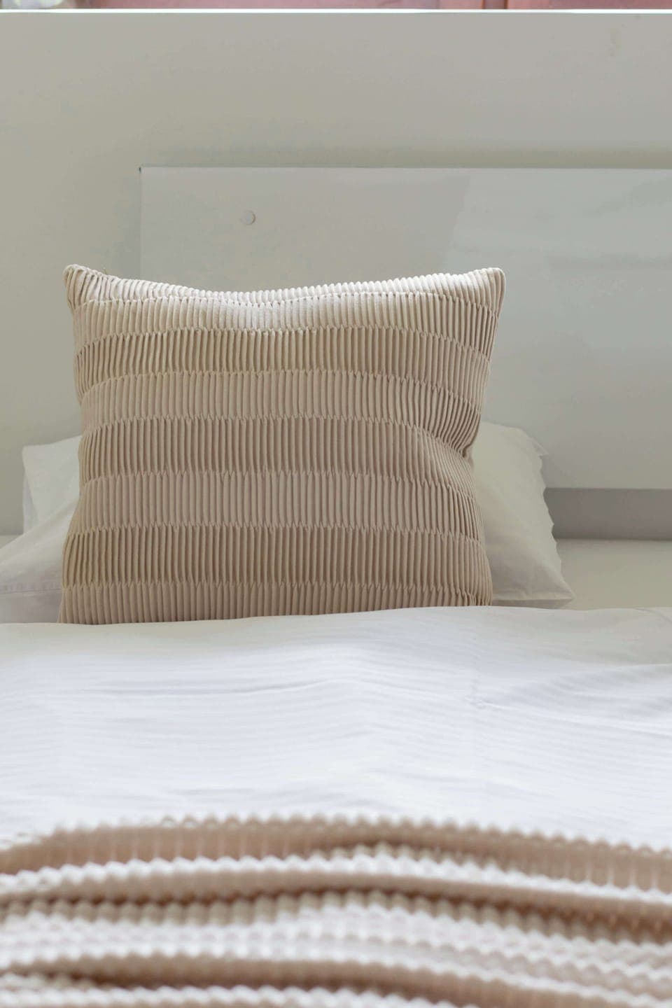 Close-up of a bed with bed linens and cushions.