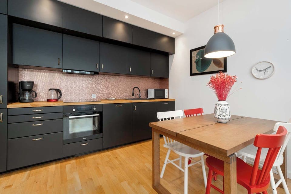 Modern kitchen with black cabinets – Fully equipped kitchen with sleek matte black cabinetry and wooden countertops.