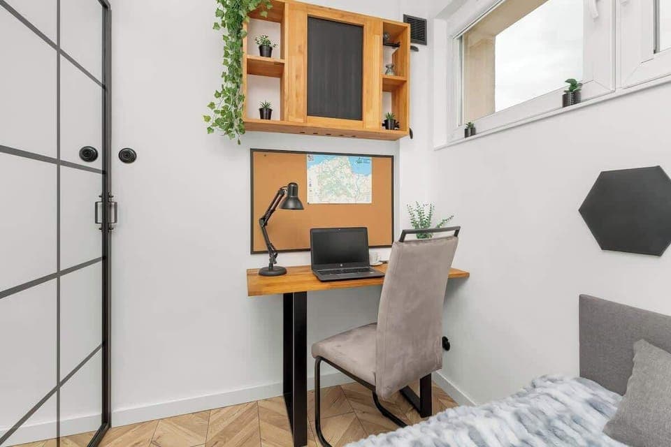 A small home office corner with white shelving, a desk, and a corkboard. The space is functional yet inviting.