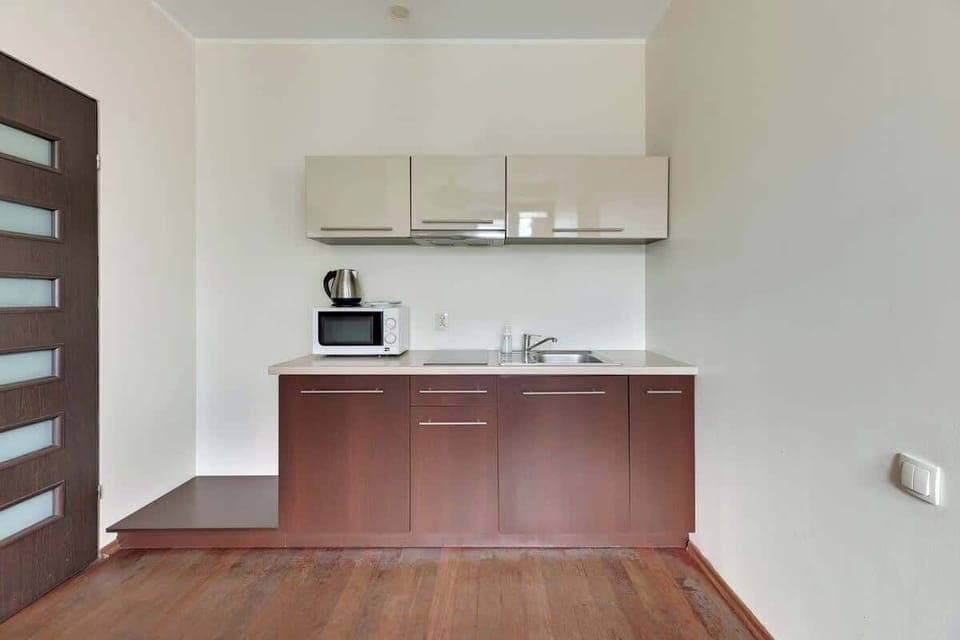 A functional kitchen featuring wooden cabinets, light countertops, and essential appliances, creating a well-organized and efficient cooking space.