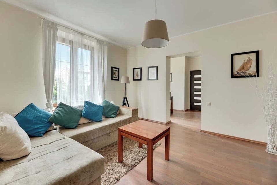 A bright and modern living room featuring a comfortable sofa, a wooden coffee table, and soft natural lighting streaming through large windows.