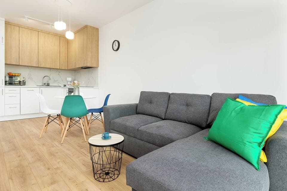 Modern open-plan living room with a dining area and kitchen in view. Bright and functional, ideal for family meals or relaxed evenings.