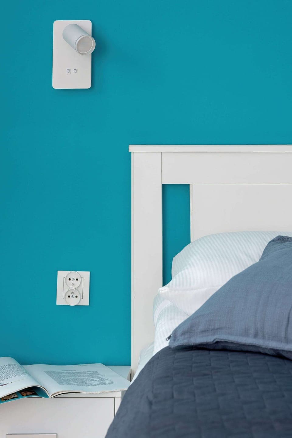Bedroom close-up with turquoise walls and a bedside lamp. Bright, clean, and welcoming for restful nights.