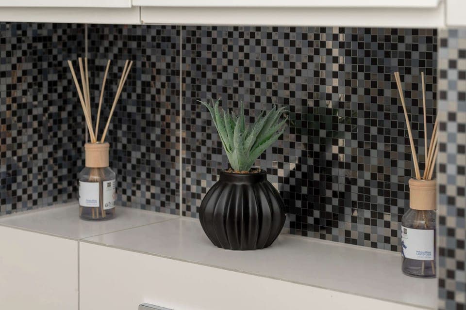 A decorative shelf above the toilet with elegant diffusers and a small artificial plant. The setup adds a refined touch to the bathroom.