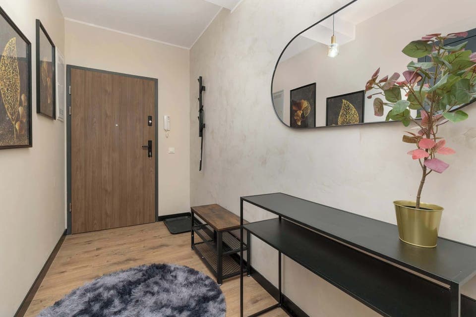 A hallway leading to an apartment, showcasing wooden floors and clean white walls.