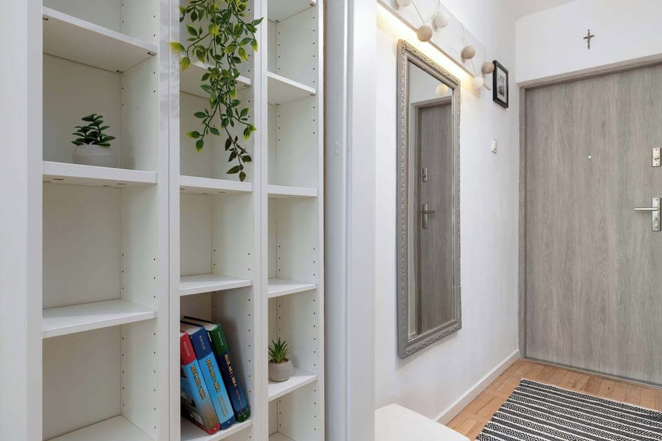 A full view of the entryway with a large mirror, coat hooks, and open shelving, emphasizing functionality and style.