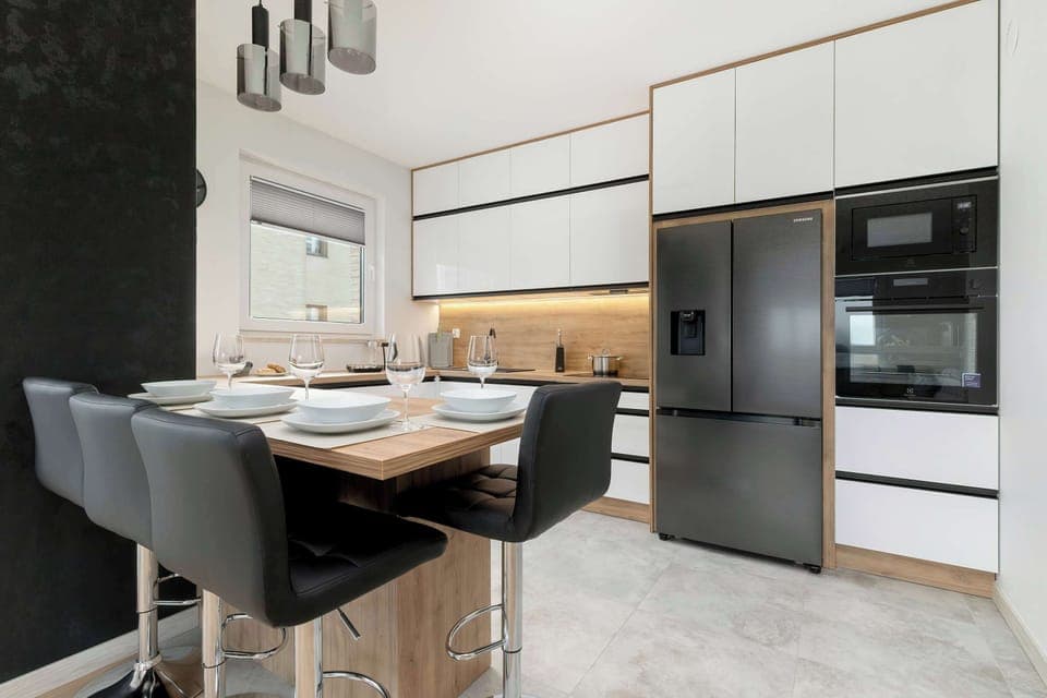 A stylish black and white kitchen with built-in appliances and a wooden backsplash. The design is sleek and modern with an elegant finish.
