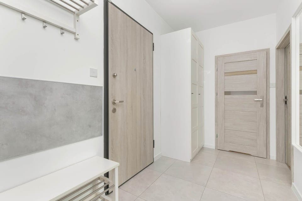 A hallway with light-colored walls and a door leading to another room, connecting spaces.