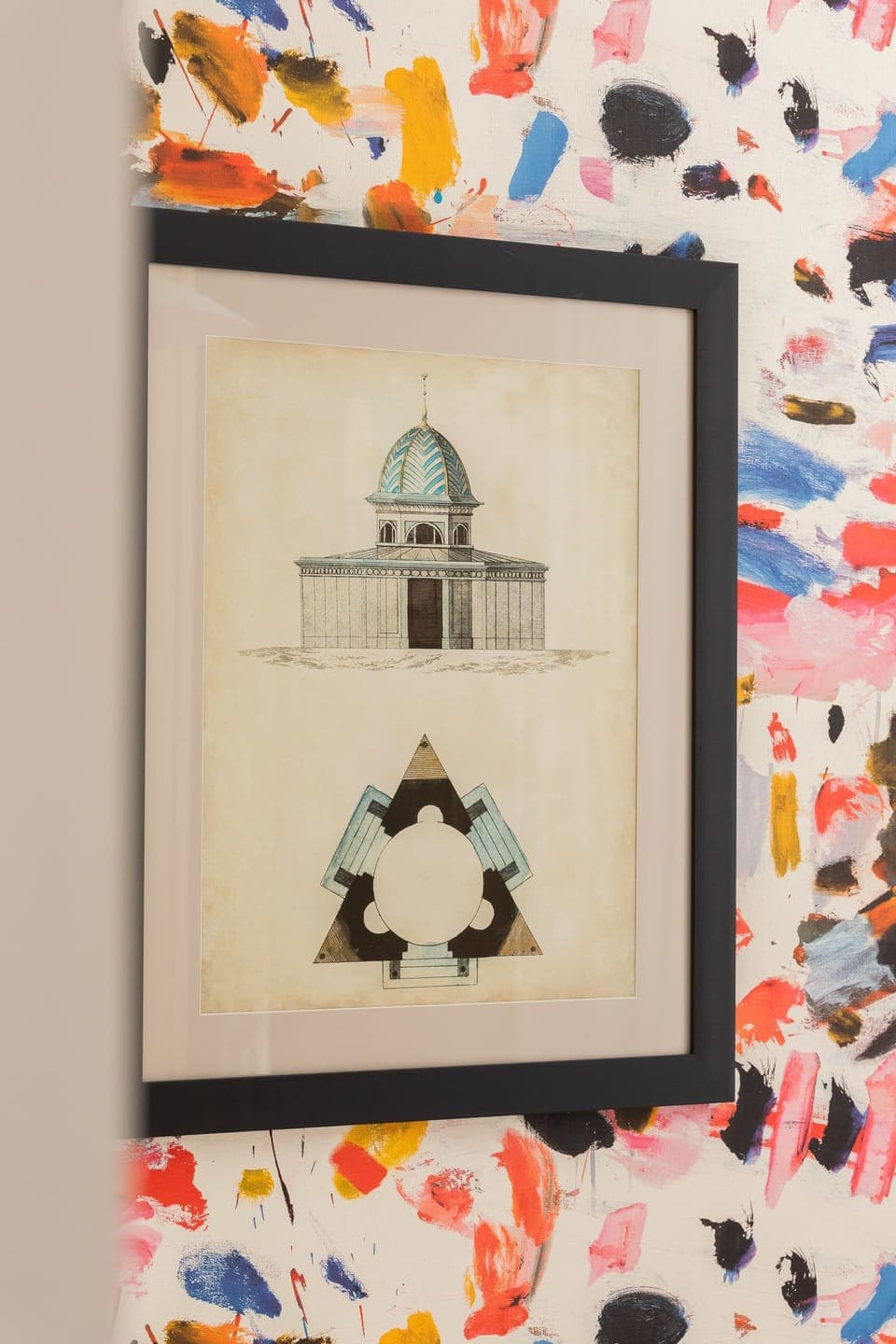 A close-up shot of framed artwork on a vibrant, floral-patterned wall.