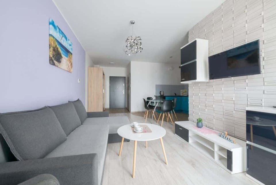 The living room is a cozy and modern space that invites you to relax in comfortable conditions. The gray sofa is not only stylish but also functional, serving as an additional sleeping space.