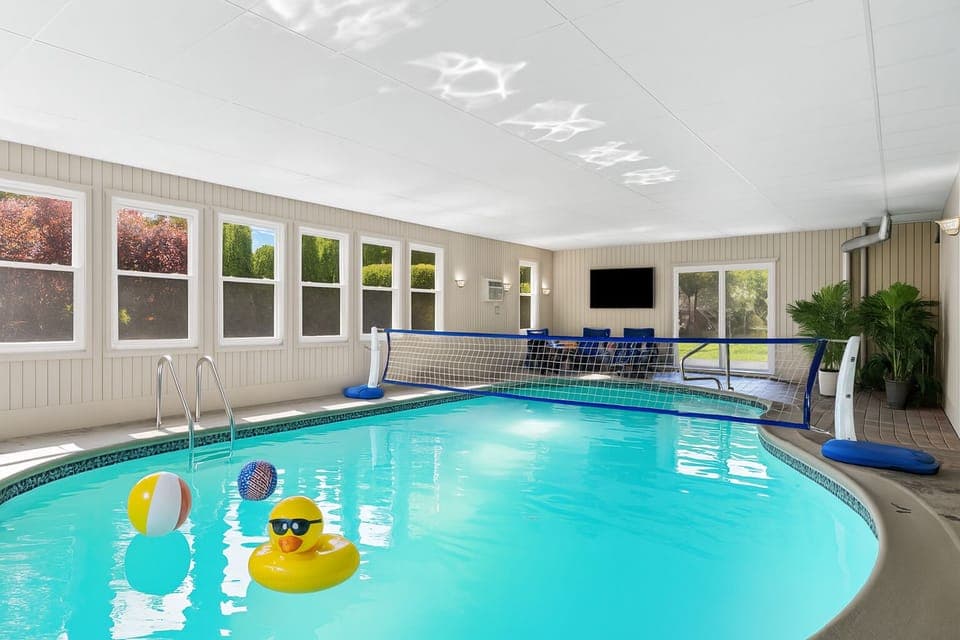 Play and unwind in your private indoor pool room with a volleyball net, floaties, lounge area, and smart TV.
